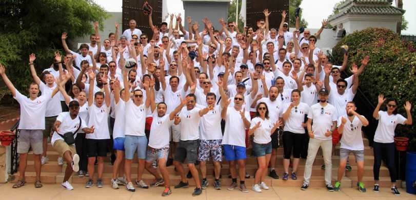 A group picture of AmeXio employees, lined up in multiple rows on a staircase with their hands in the air.