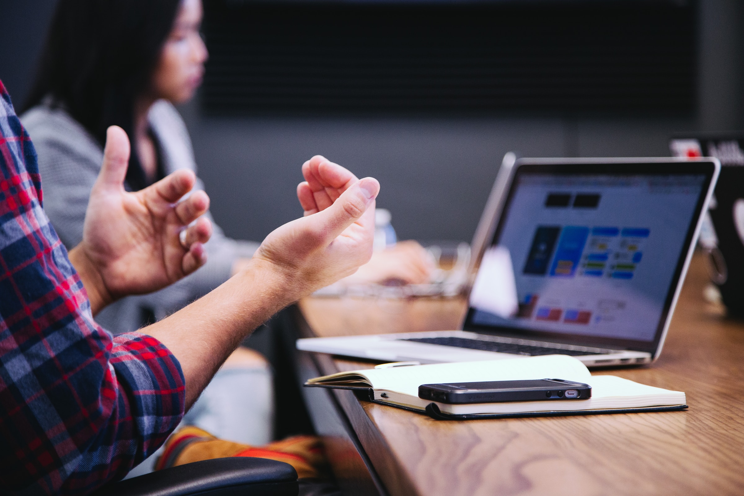 Picture of a person gesturing while sitting in front of a laptop.