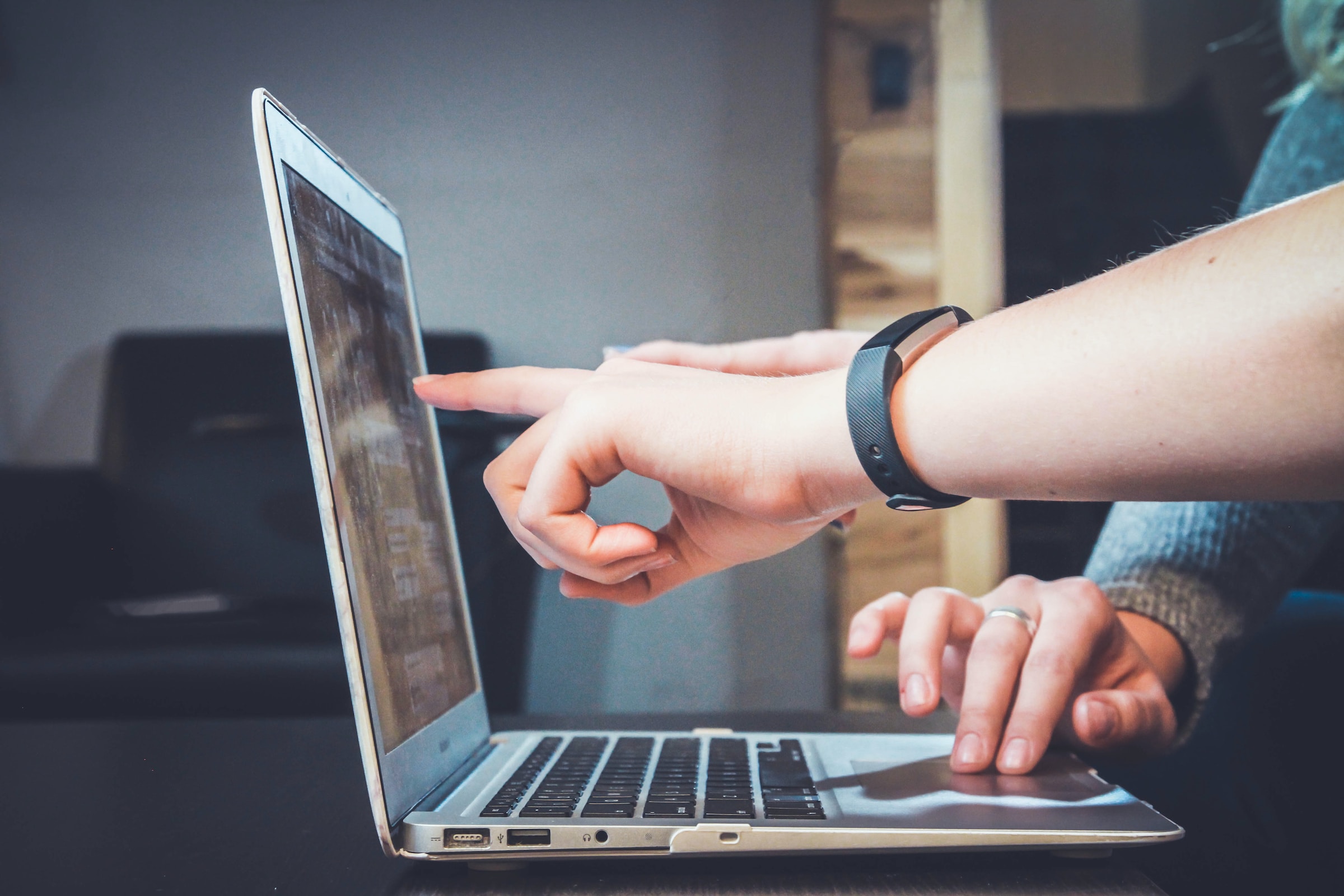 Hand pointing at laptop screen