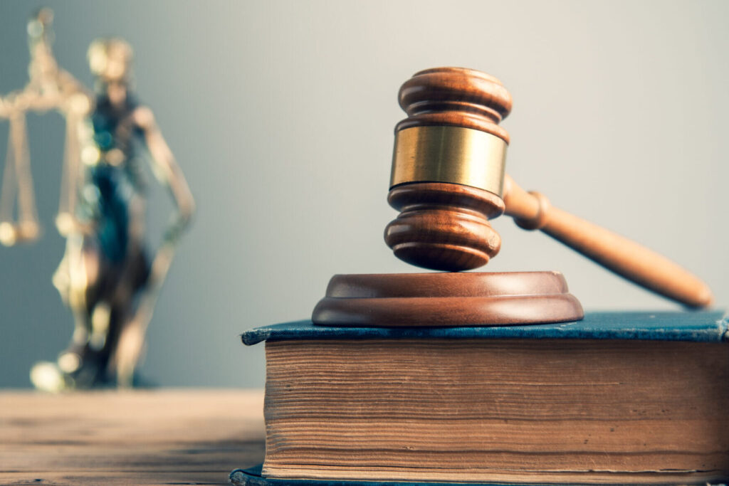 wooden judge hammer on lawbook with lady justice on desk