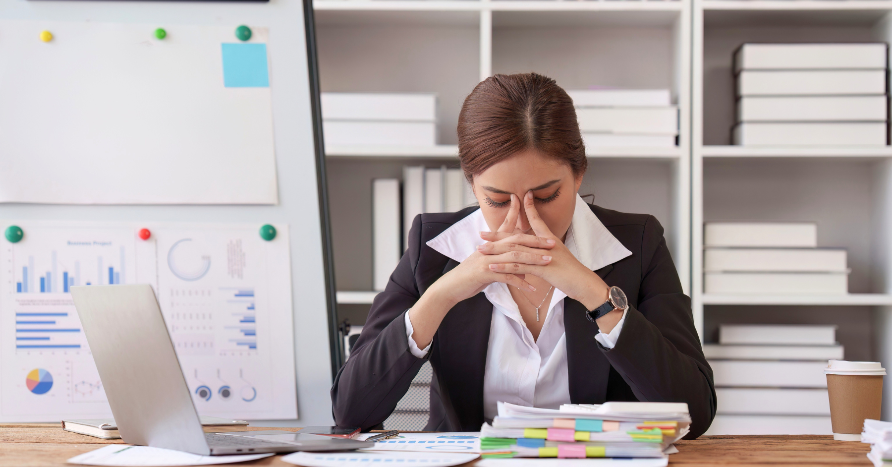 A woman in business clothes looking stressed while surrounded by papers